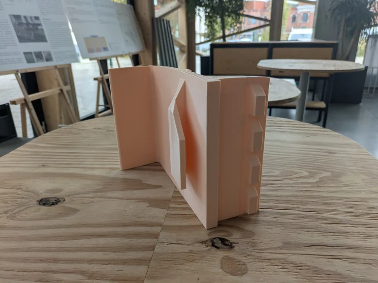 Large curved 3D printed part in salmon PLA on a wooden table at the MadeInBXL workshop in Brussels