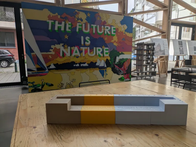 3D printed concrete bench mould on a wooden table in front of a colourful mural at the GreenBizz workshop in Brussels